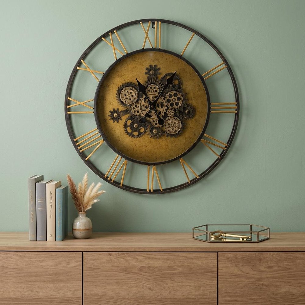 28" Circle Copper Metal and Glass Analog Exposed Gear Wall Clock shown outdoors on an outdoor setting with greenery in light gray glass.