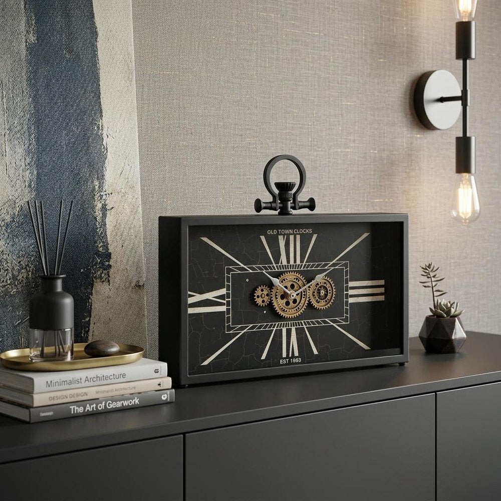 13" Black and Gold Metal and Glass Analog Vintage Style Crackle Wall Clock styled in a furnished interior with a tan wall on a charcoal floor.