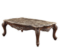 Rectangular coffee table with a faux marble top and dark wood base with ornate carvings on a white background.