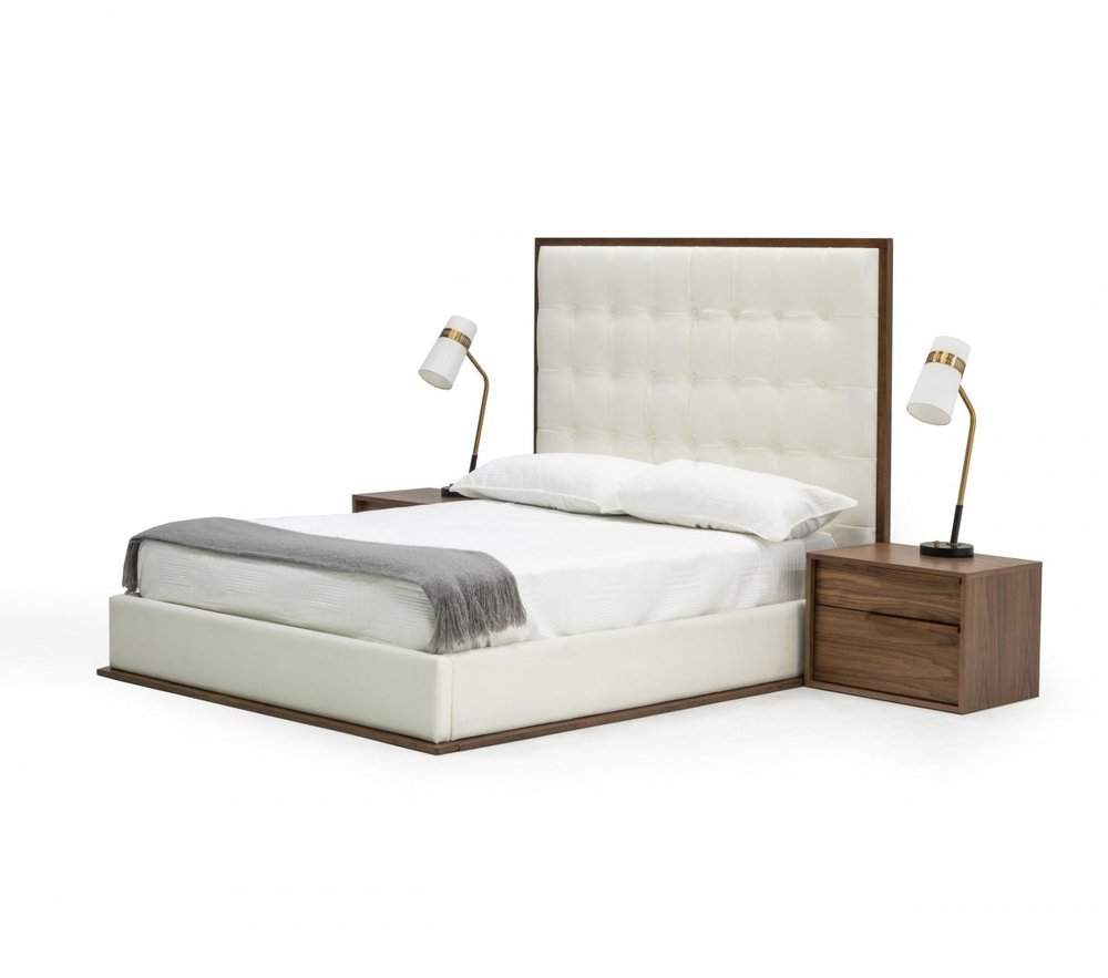 King size bed frame with white tufted faux leather headboard and white upholstery, on a white background with two wooden nightstands and lamps.