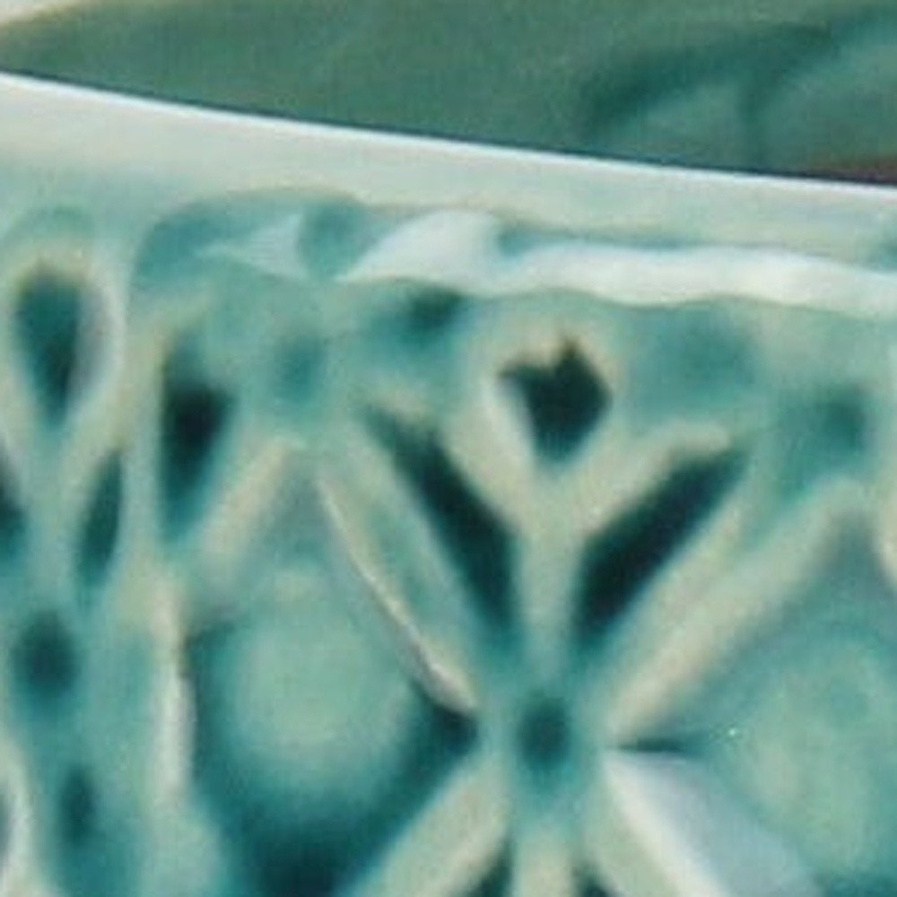 6" Turquoise Geometric Ceramic Indoor Outdoor Round Pot Planter shown outdoors on a patio with greenery in teal ceramic.