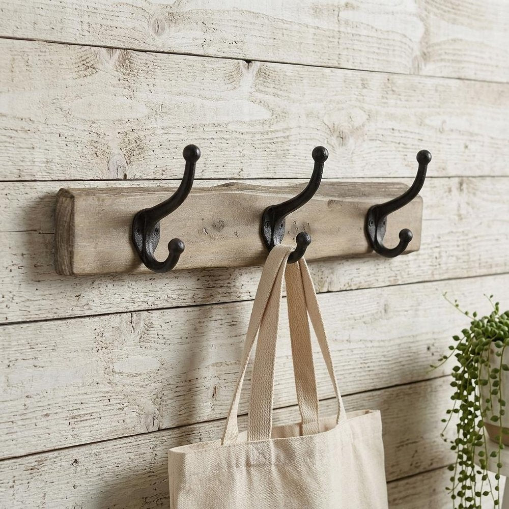 19" Brown Natural Rustic Live Edge Wood Three Hook Wall Mount Coat Rack styled in a furnished interior with an off-white wall on a wood floor.