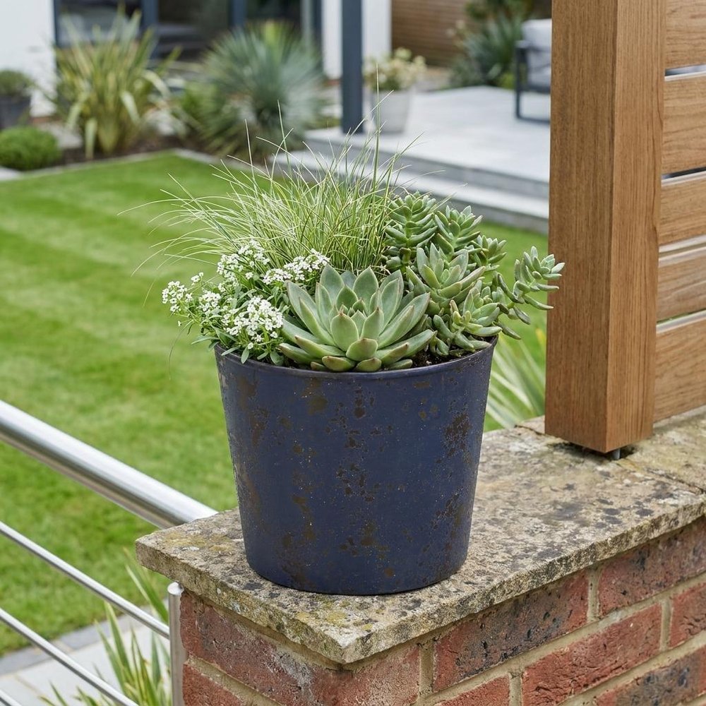 6" Blue Recycled Plastic Indoor Outdoor Round Pot Planter shown outdoors on a patio with greenery.