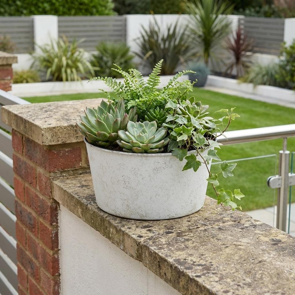 12" Cream Recycled Plastic Indoor Outdoor Round Pot Planter shown outdoors on a patio with greenery.