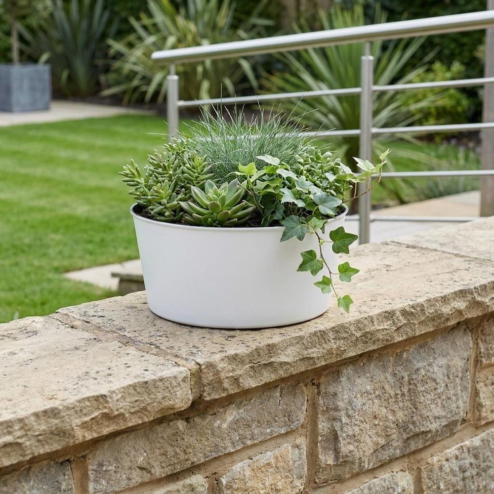 12" White Recycled Plastic Indoor Outdoor Round Pot Planter shown outdoors on a patio with greenery.