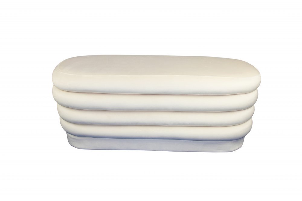 White velvet tufted oval ottoman on a white background.