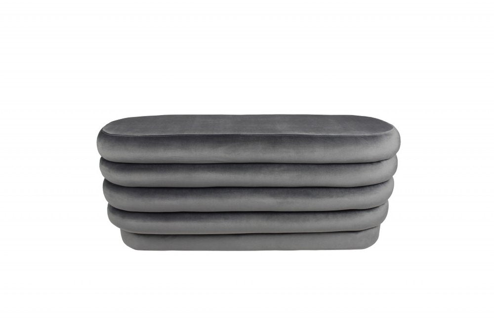 Gray velvet tufted oval ottoman stacked on a white background.