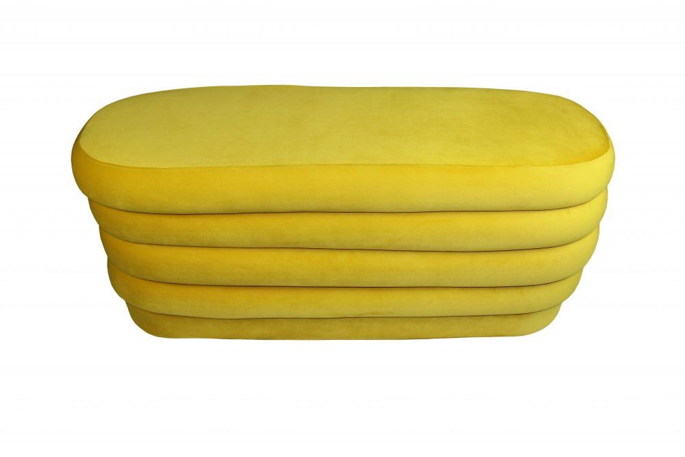 Yellow velvet tufted oval ottoman on a white background.