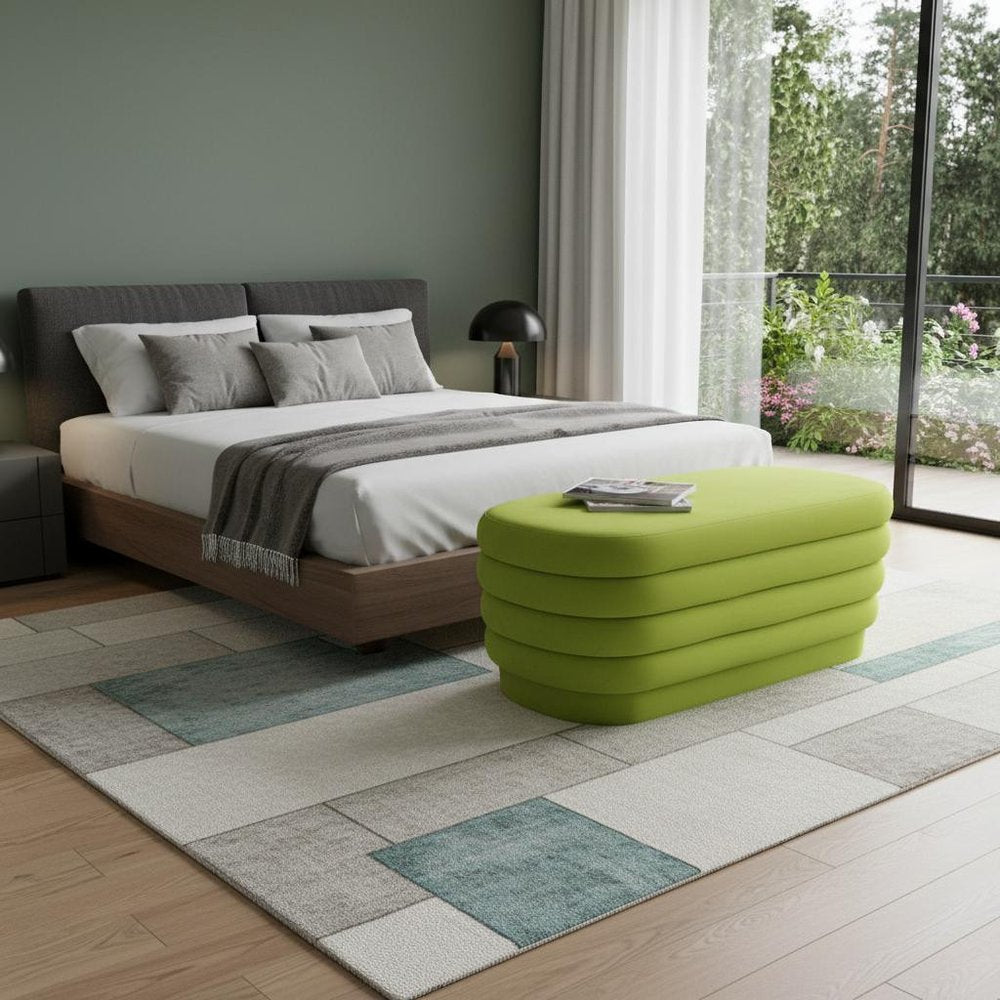 44" Green Velvet Tufted Oval Ottoman styled in a furnished interior with a gray wall on a wood floor.