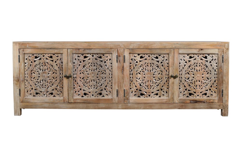 Natural distressed solid wood TV stand with four carved floral doors and brass knobs on a white background.