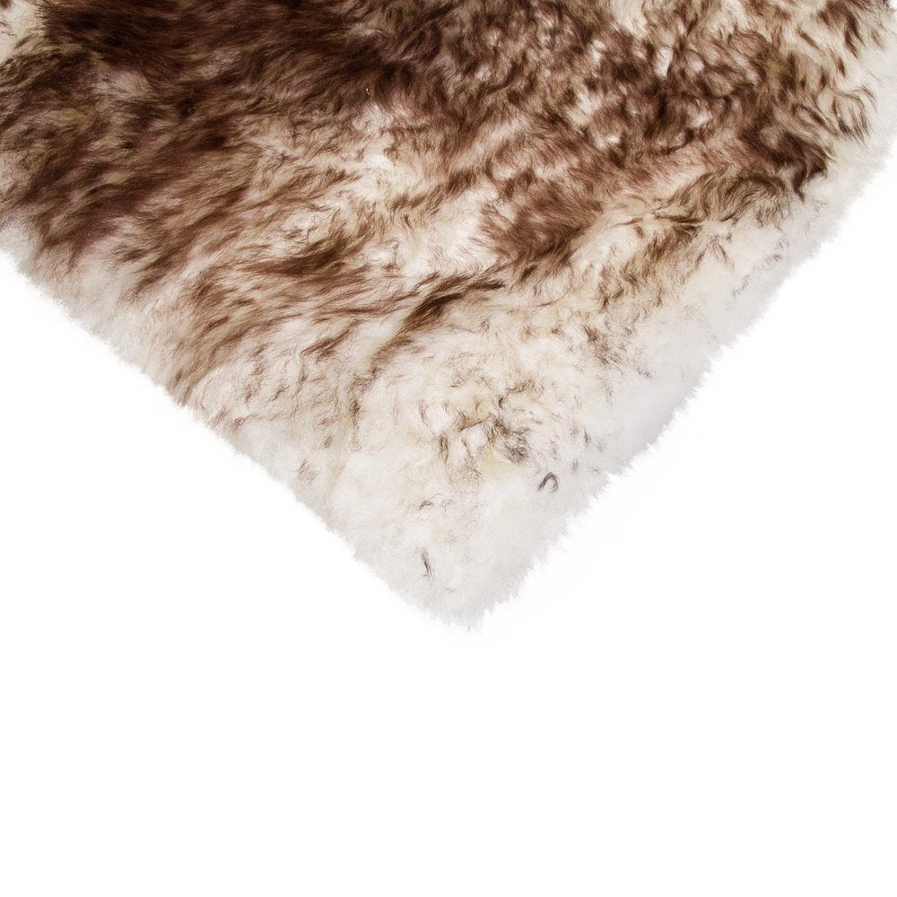 Close-up of a fluffy sheepskin rug with brown and white gradient coloring on a white background.