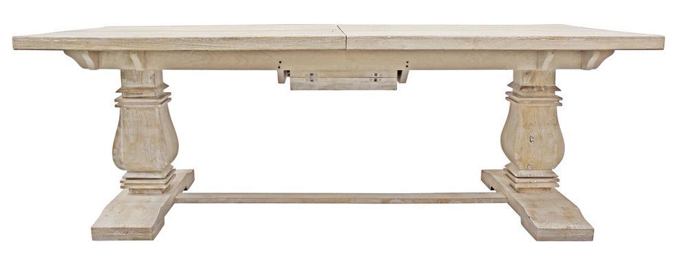 A light-colored solid wood dining table with a rustic finish and ornate pedestal legs, shown on a white background.