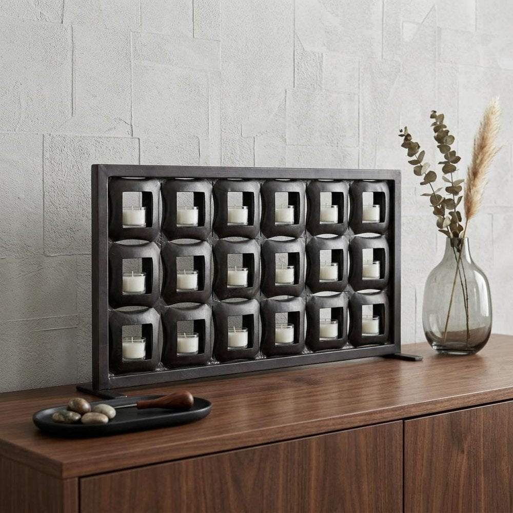 23" Black Iron Geometric Floor Tealight Candle Holder displayed on a dark wood tabletop in a furnished interior against an off-white wall.