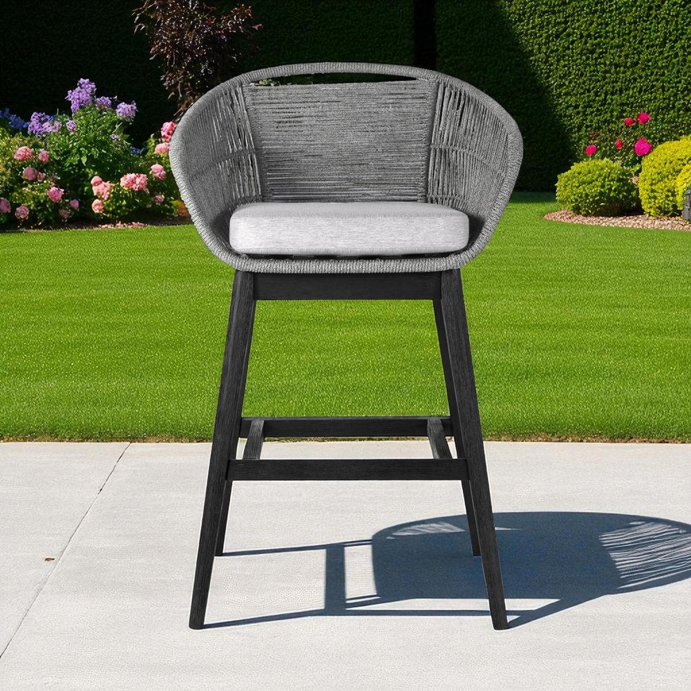 43" Light Gray Solid Wood Low back Outdoor Bar Height chair with Footrest shown outdoors on a patio with greenery.