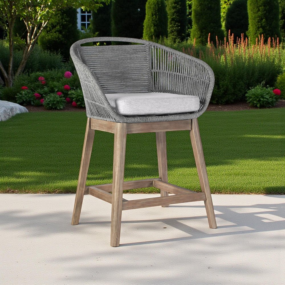 38" Light Gray Solid Wood Low back Outdoor Bar Height chair with Footrest shown outdoors on a tiled patio with greenery.