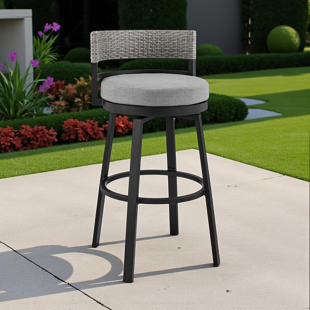 38" Light Gray Metal Swivel Low back Outdoor Bar Height chair with Footrest shown outdoors on a tiled patio with greenery.