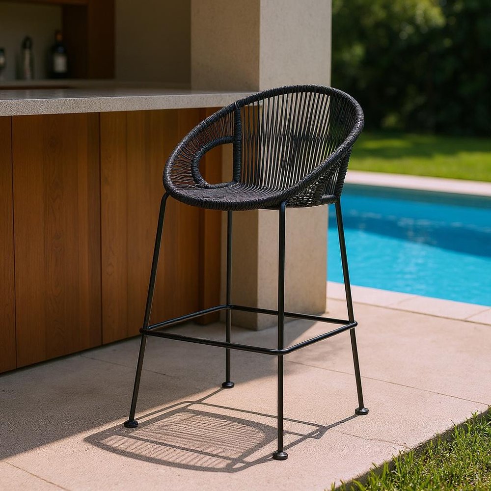 40" Black Metal Low back Outdoor Counter Height Bar chair with Footrest styled in a furnished interior with a dark brown wall on a blush floor.
