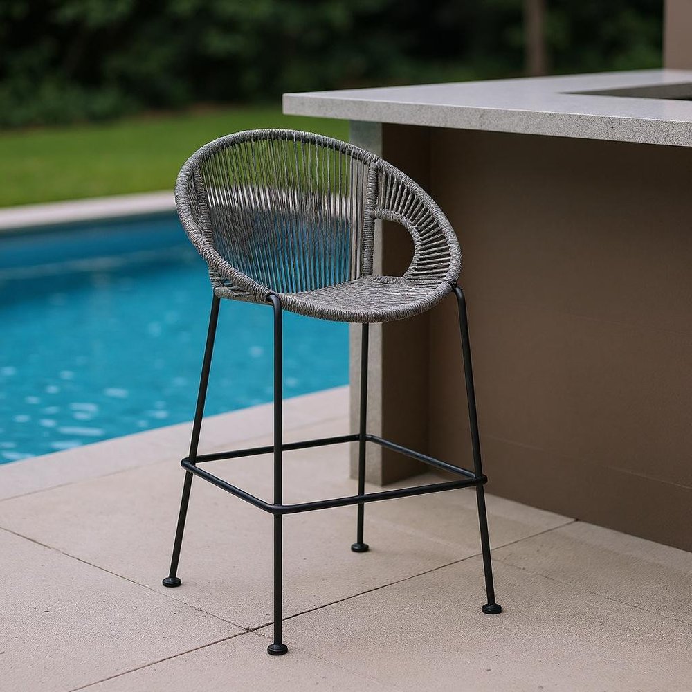 40" Light Gray Metal Low back Outdoor Counter Height Bar chair with Footrest shown outdoors on a tiled patio with greenery.
