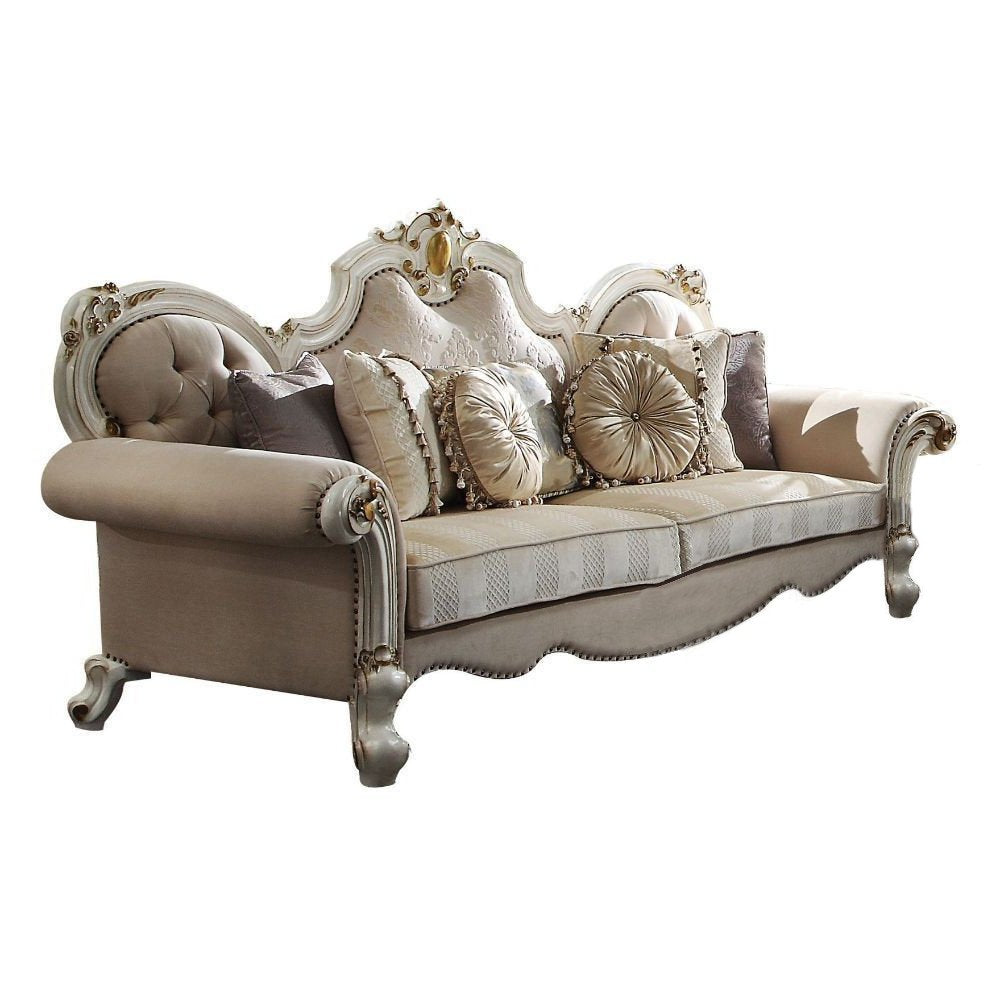 A luxurious cream velvet sofa with ornate gold accents and decorative toss pillows on a white background.