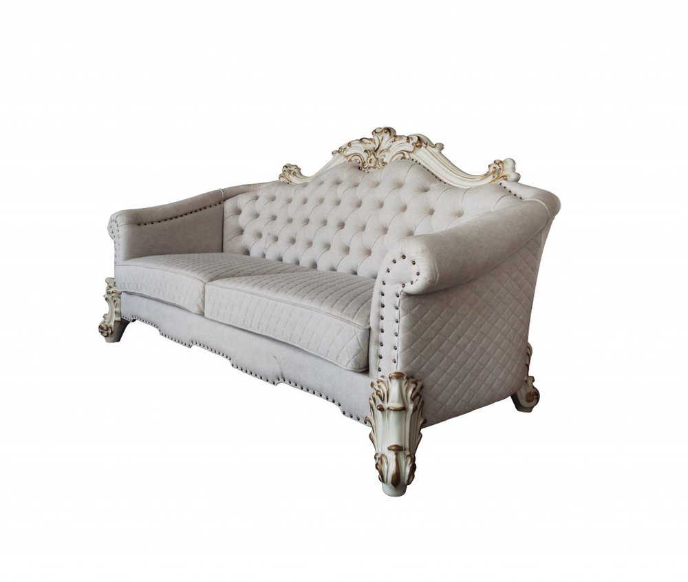 A tufted ivory sofa with ornate pearl legs and gold accents on a white background.