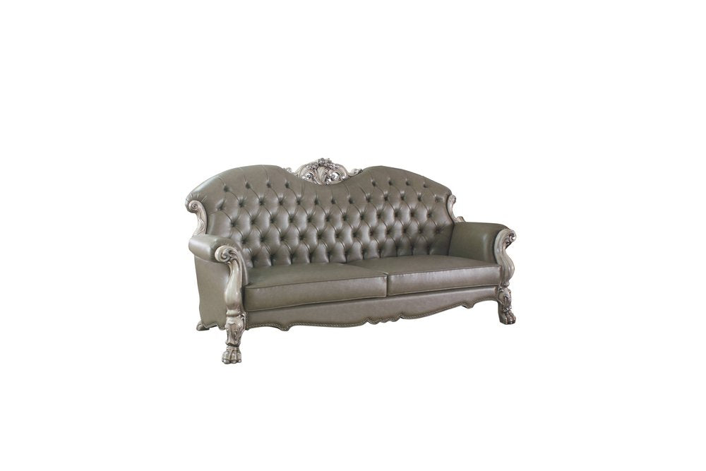 A tufted grey faux leather sofa with ornate carved legs and a decorative crest on a white background.