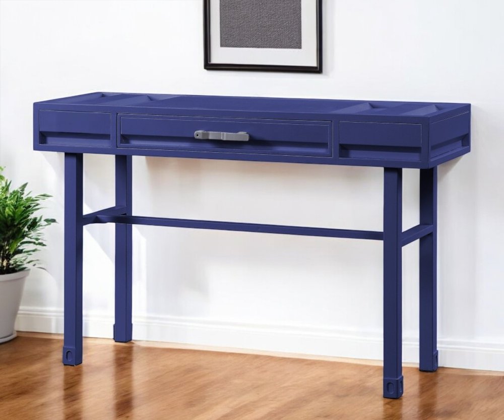 Blue iron and wood console table with one drawer and a shelf, set against a white wall and wooden floor.