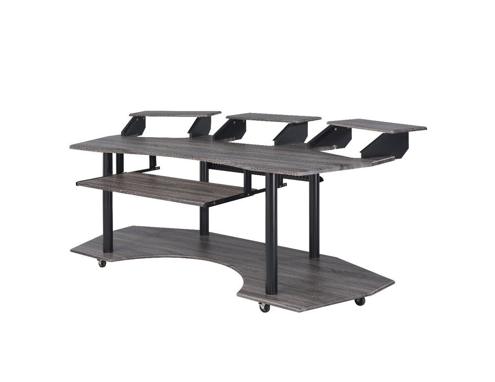 A dark gray wood recording studio desk with black metal legs and wheels, featuring multiple shelves and risers, on a white background.
