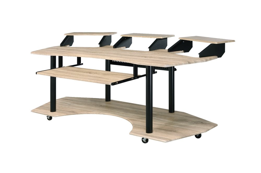 A light wood recording studio desk with black legs and wheels, featuring multiple shelves and a pull-out keyboard tray.