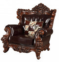 Espresso faux leather tufted wingback chair with ornate wood trim and a patchwork toss pillow on a white background.
