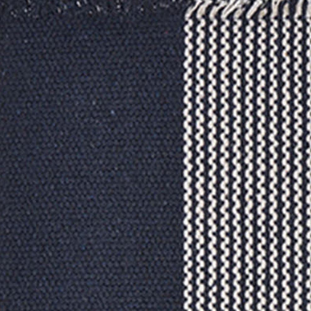 19" Set of Four Navy Blue And White Striped Cotton Placemats styled in a furnished interior with a dark wall on a charcoal floor.