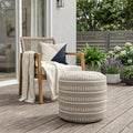20" Green Polyester Round Striped Indoor Outdoor Pouf Ottoman shown outdoors on a patio with greenery.
