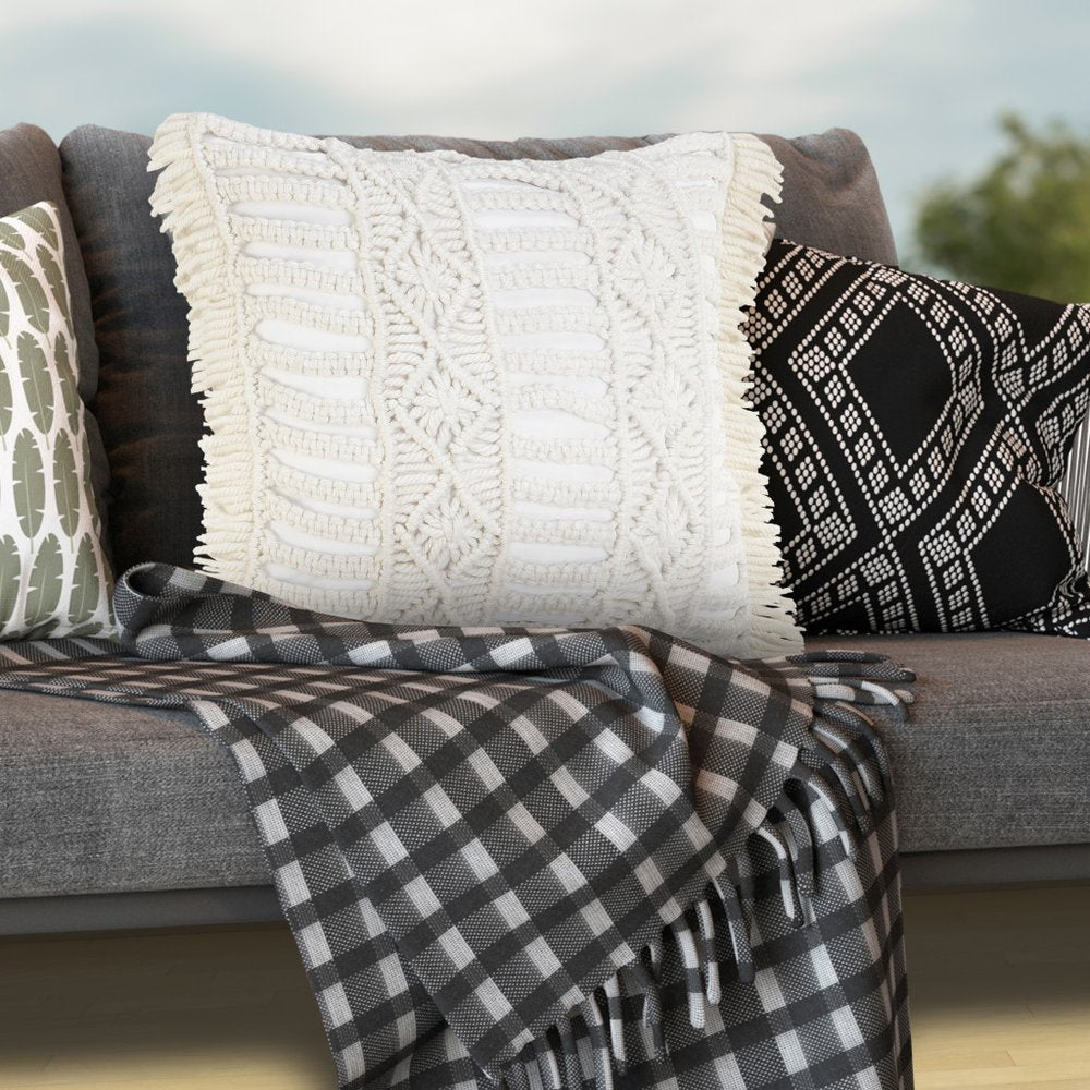 24" X 24" White Zippered Tropical Indoor Outdoor Throw Pillow styled in a furnished interior with an off-white wall on a charcoal floor.