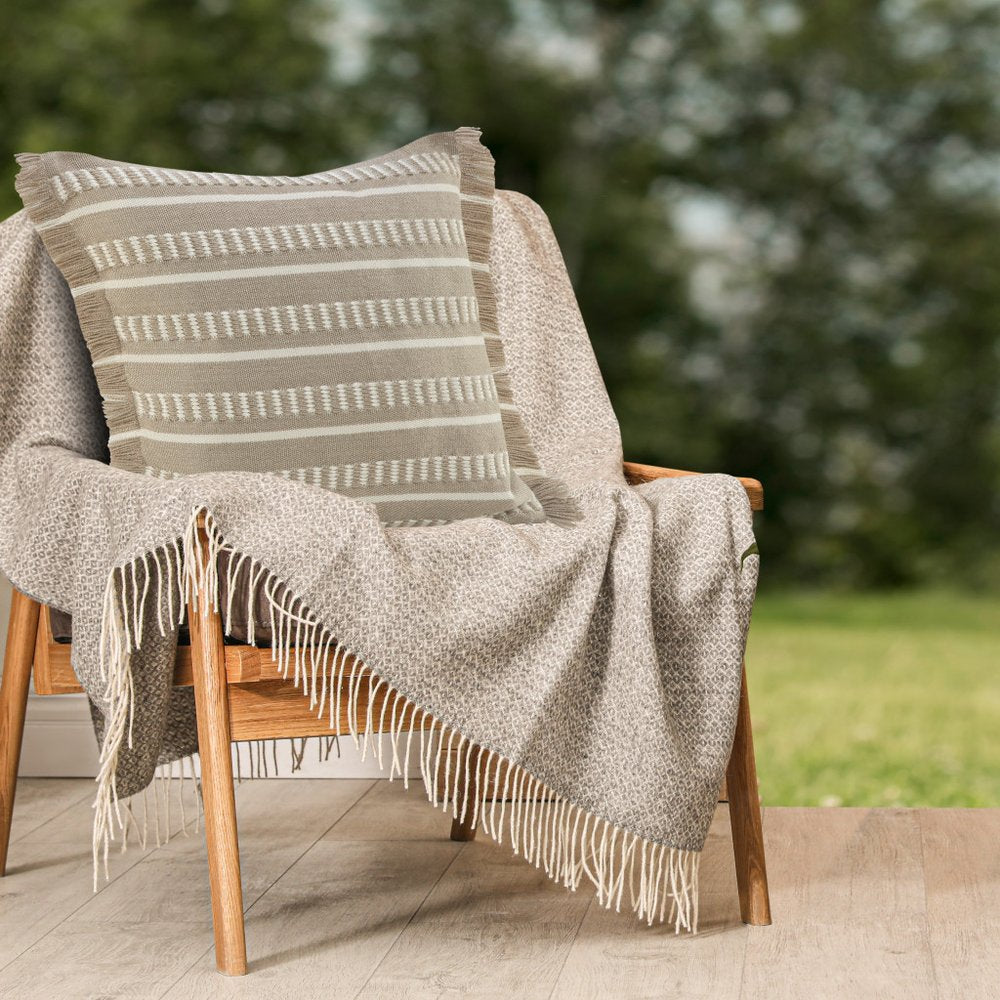 24" X 24" Tan Zippered Coastal Indoor Outdoor Throw Pillow styled in a furnished interior with a olive wall on a wood floor.