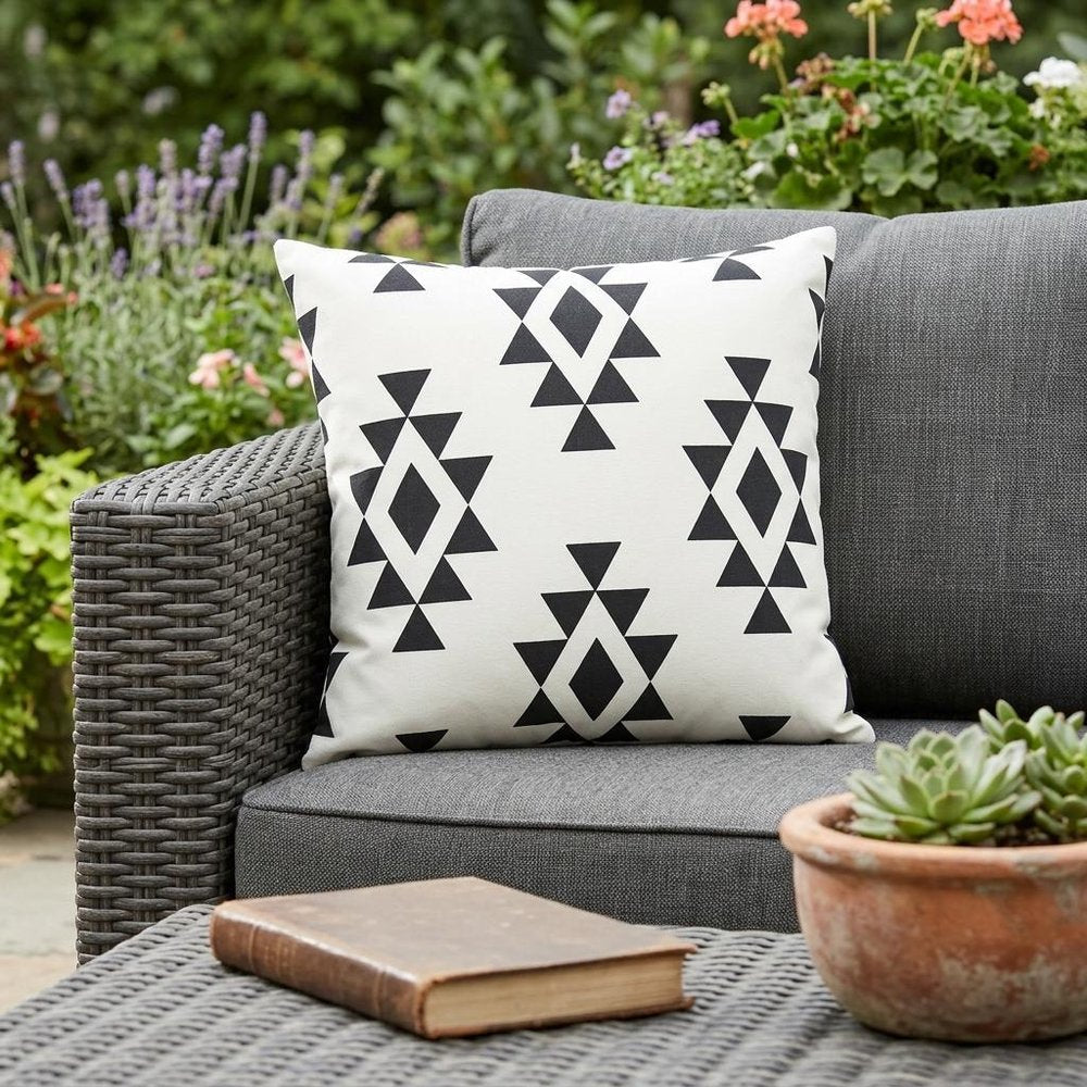 20" X 20" Black Zippered Southwestern Indoor Outdoor Throw Pillow shown outdoors on a tiled patio with greenery.