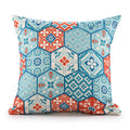 A square throw pillow with a blue, red, and white hexagonal patchwork pattern on a white background.
