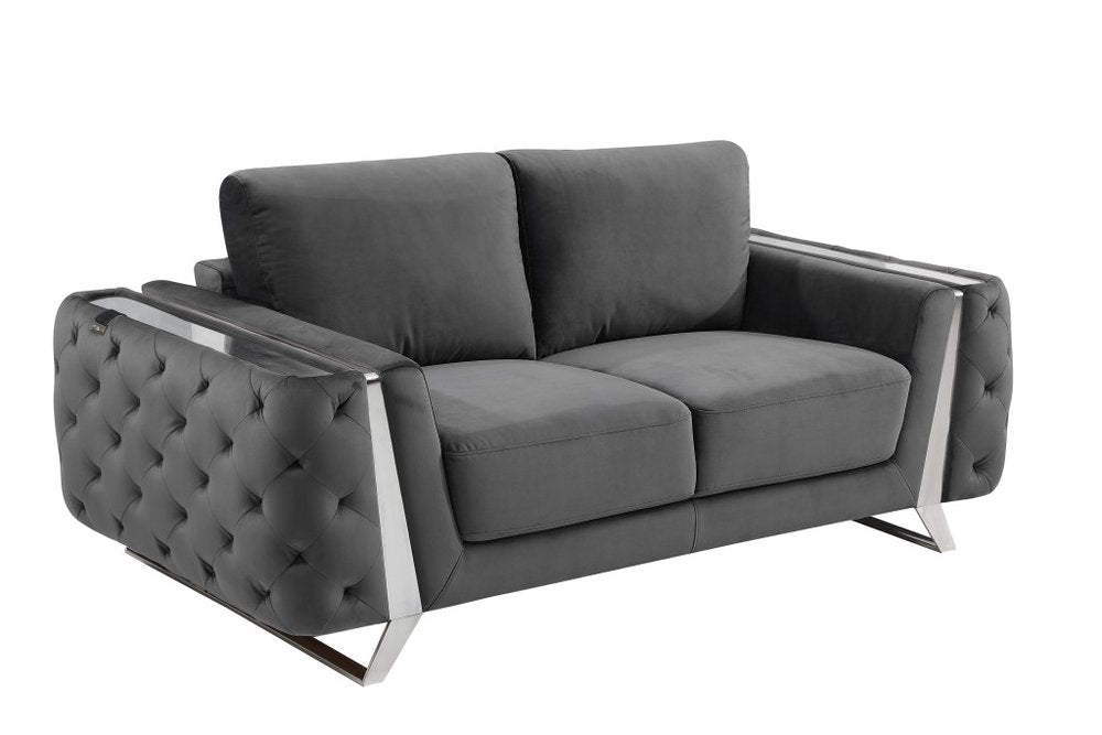 Dark gray velvet loveseat with tufted sides and silver metal accents on a white background.