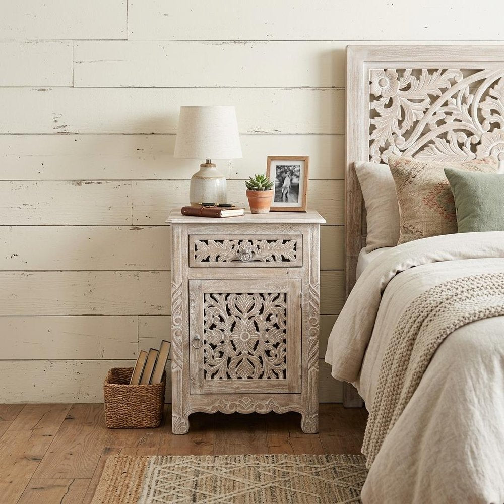 30" Distressed White One Drawer Carved Floral Solid Wood Nightstand styled in a furnished interior with an off-white wall on a wood floor.