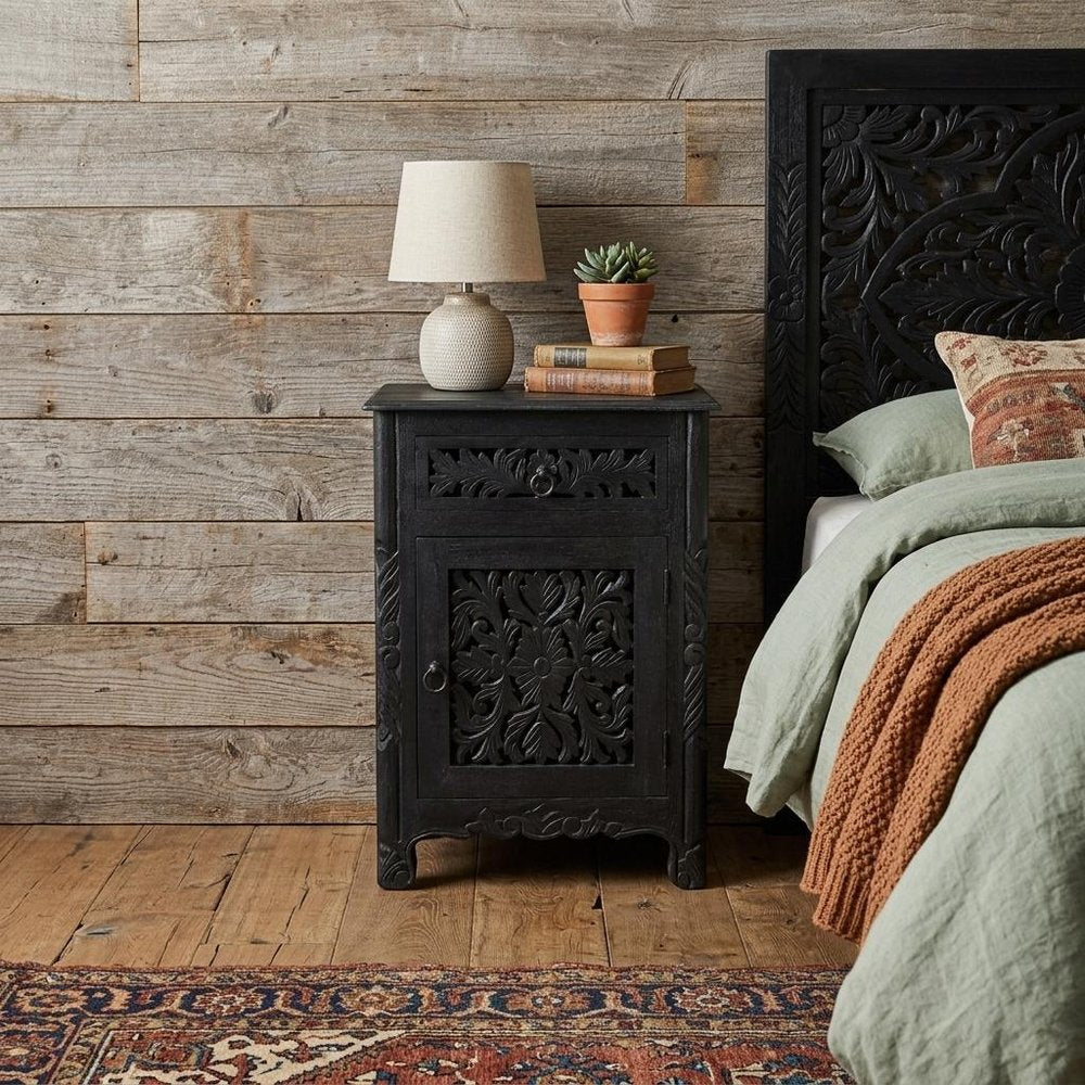 30" Black Solid Wood Distressed One Drawer Nightstand styled in a furnished interior with a tan wall on a dark wood floor.