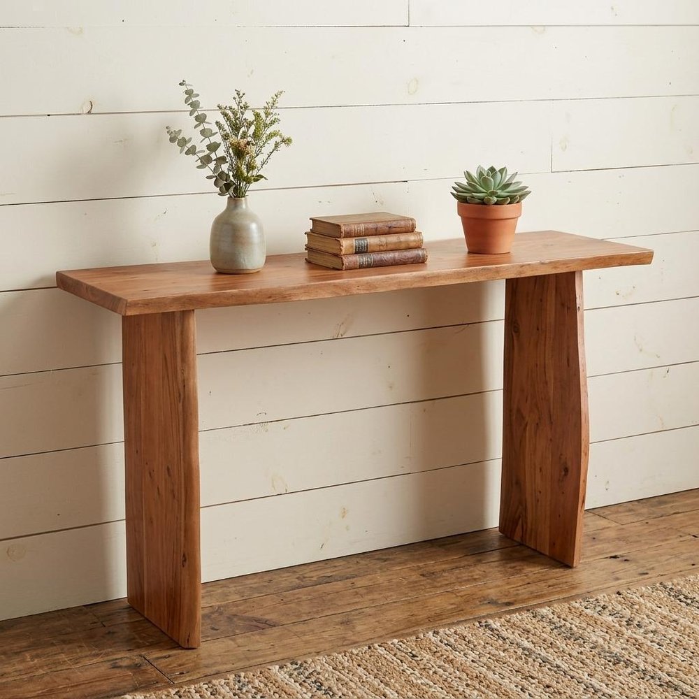57" Chestnut Solid Wood Sled Console Table styled in a furnished interior with an off-white wall on a wood floor in tan wood.