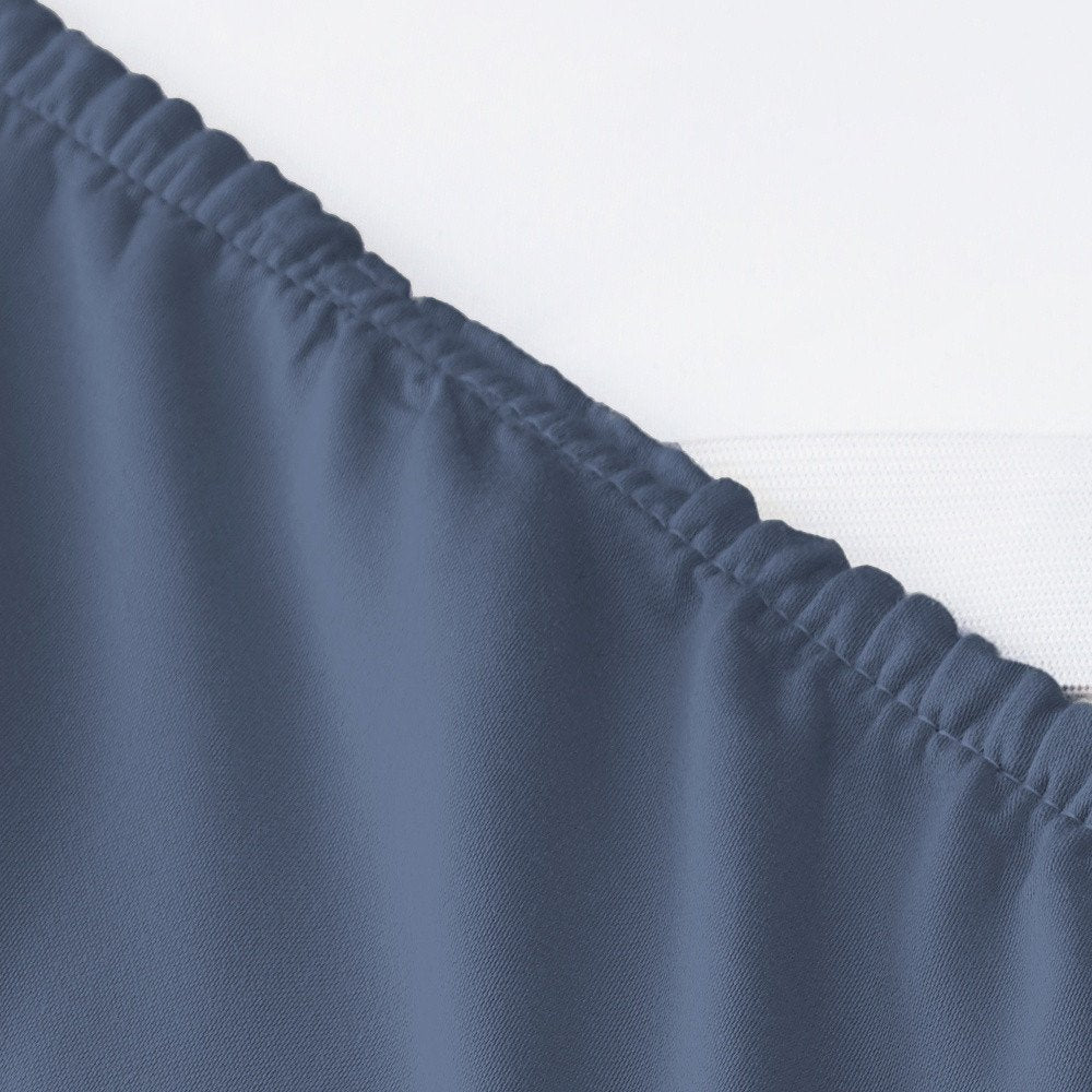 Close-up of a blue Tencel Lyocell queen sheet set with a ruffled edge against a white background.