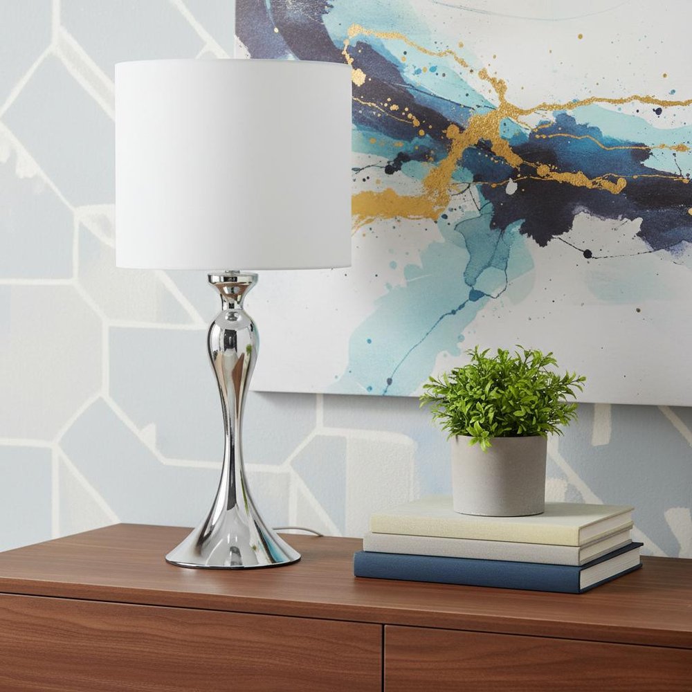 25" Silver Sleek Table Lamp With Off White Drum Shade shown outdoors on an outdoor setting in off-white.