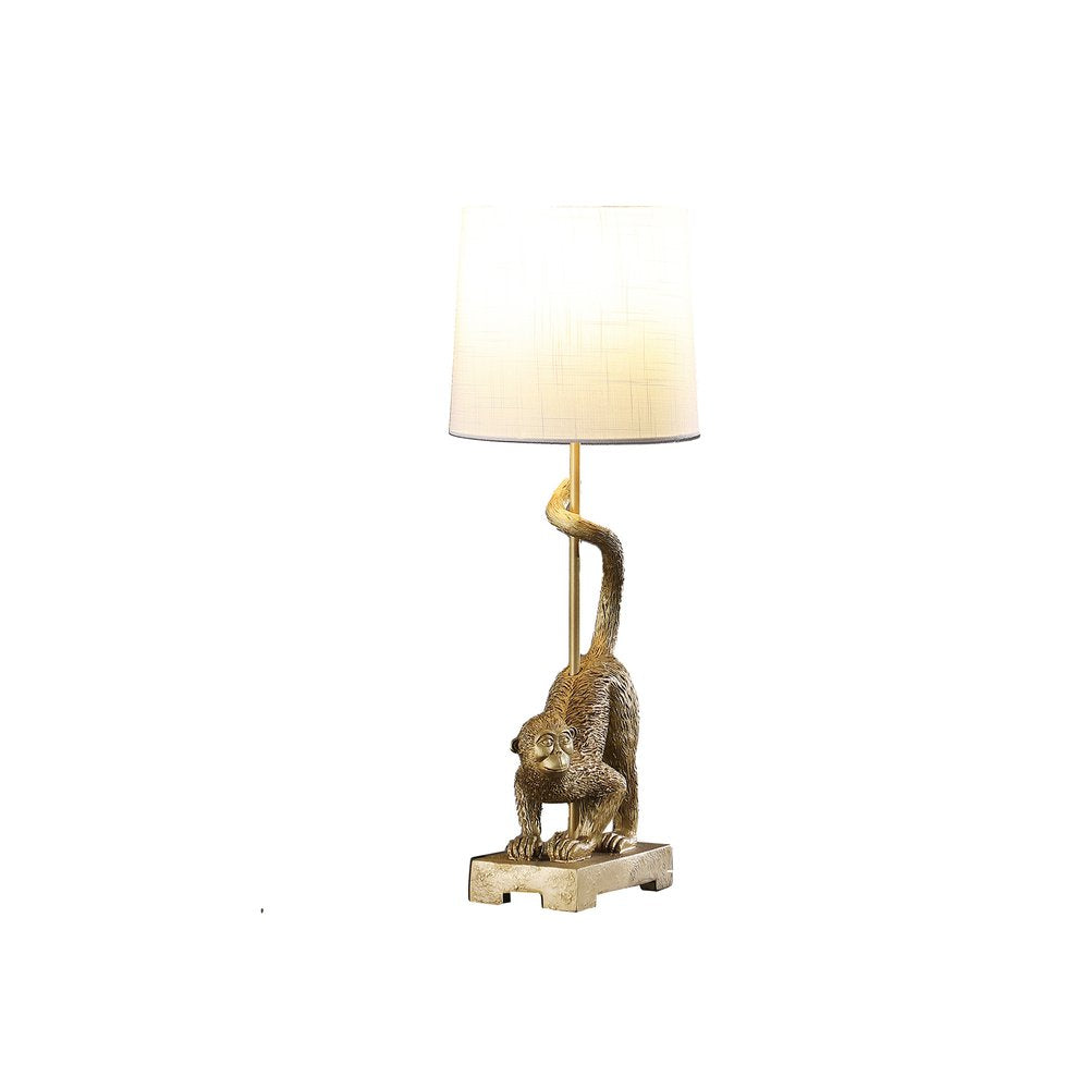 24" Gold Monkey Table Lamp With White Drum Shade. Table lamp isolated on a plain white background, finished in gold.