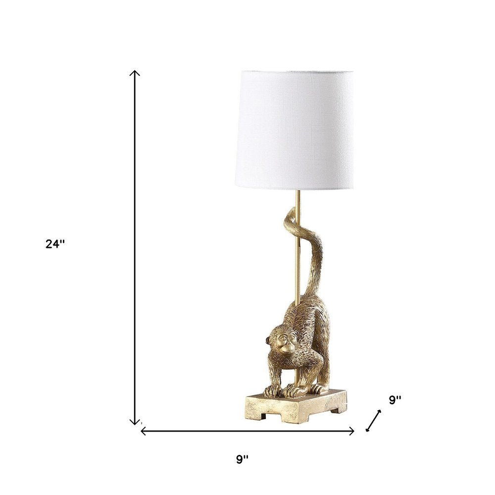 24" Gold Monkey Table Lamp With White Drum Shade. Table lamp isolated on a plain white background, finished in gold.