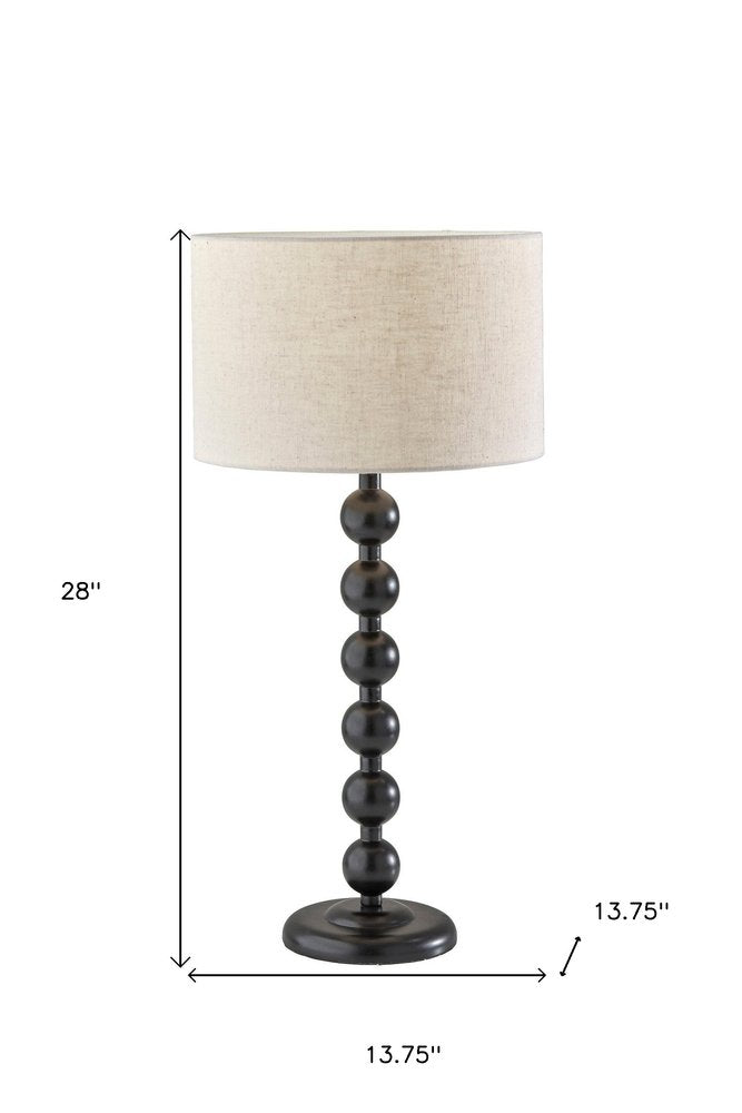 28" Black Solid Wood Candlestick Table Lamp With Off White Drum Shade. Table lamp isolated on a plain white background, showing a off-white wood surface.