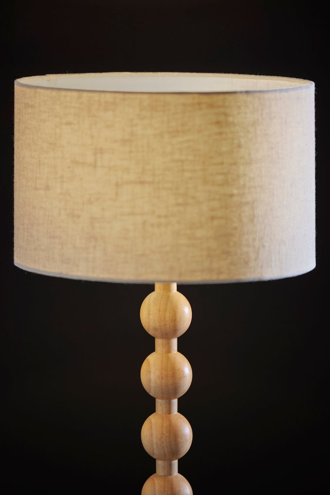 28" Brown Solid Wood Candlestick Table Lamp With Off White Drum Shade photographed against a dark studio background in off-white.