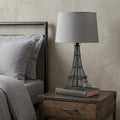 25" Black Acrylic Paris Desk Table Lamp With Gray Drum Shade displayed on a dark wood tabletop in a furnished interior against a light gray wall.