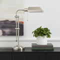 26" Nickel Metal Adjustable Table Lamp With Nickel Rectangular Shade displayed on a tabletop in a furnished interior against an off-white wall.
