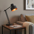 33" Black Metal Adjustable Desk Table Lamp displayed on a dark wood tabletop in a furnished interior against a tan wall.