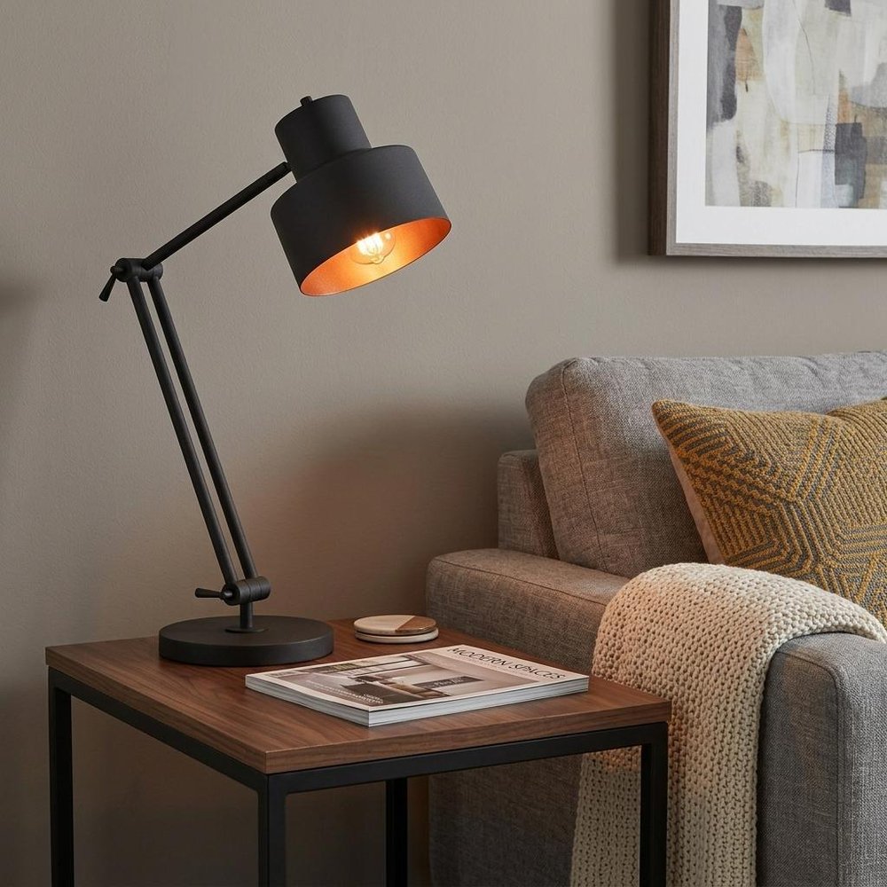 33" Black Metal Adjustable Desk Table Lamp displayed on a dark wood tabletop in a furnished interior against a tan wall.