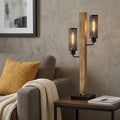 32" Gray Metal Two Light Table Lamp With Black Novelty Shade displayed on a dark wood tabletop in a furnished interior against a tan wall.